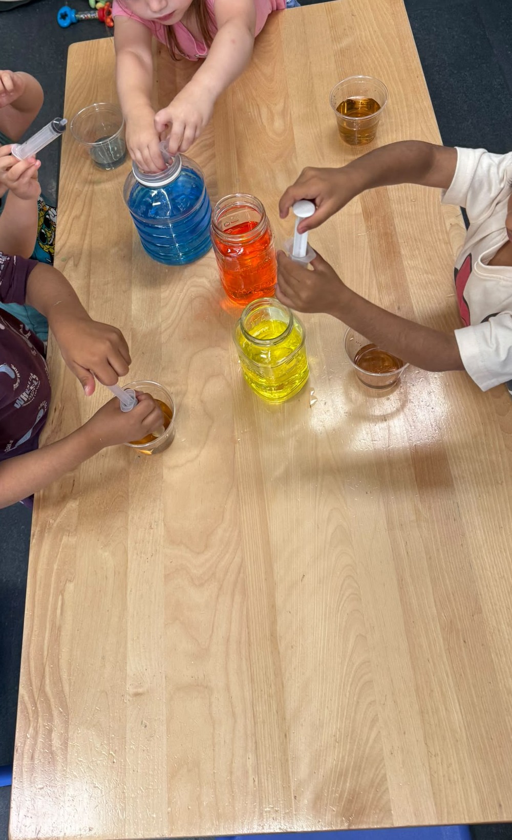 Children using droppers to mix coloured water in jars during a colour science experiment